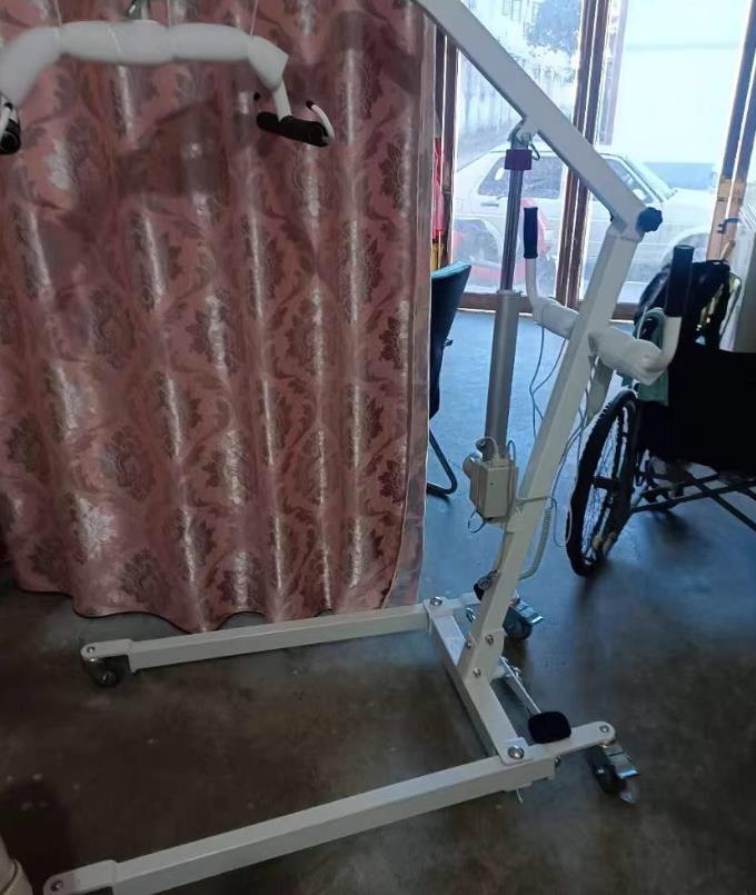 Pfleger nutzt Patientenliftsysteme, um den Patienten sicher vom Bett in den Rollstuhl zu transportieren
